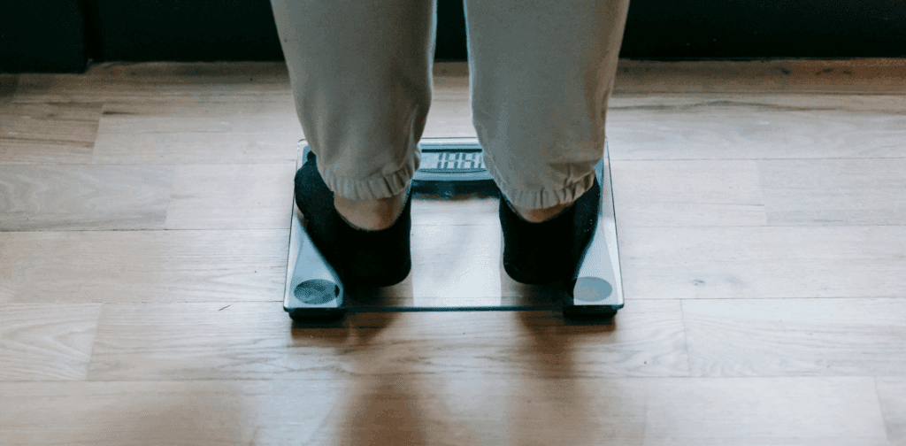 Person stepping on a scale representing the weight loss benefits of water fasting and metabolic reset
