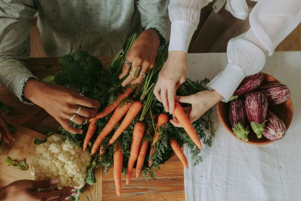 Fresh whole vegetables including carrots, broccoli, cauliflower, and eggplant on a wooden table