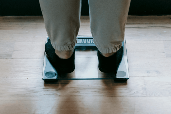 Person stepping on a scale representing the weight loss benefits of water fasting and metabolic reset
